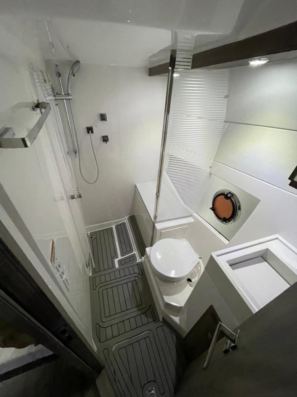 Modern bathroom in 2021 Evolve 400HT yacht with shower, sink, and porthole.