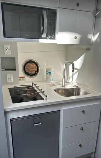 Seas The Moment Yacht Photos Pics Compact modern kitchen in 2021 Evolve 400HT with stove, sink, and microwave.