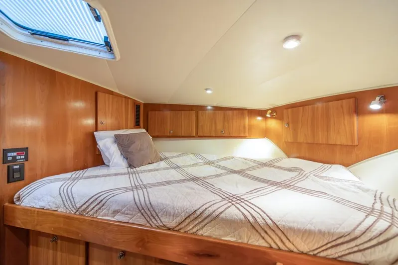 Restless II Yacht Photos Pics Cozy cabin bedroom in 2007 Navigator Classic 48 yacht with wood paneling and skylight.