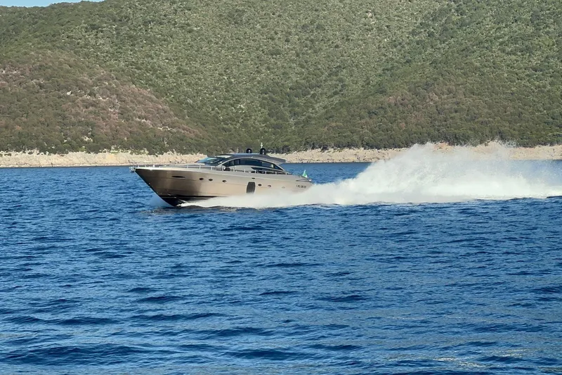  Yacht Photos Pics 2008 Pershing 72 yacht cruising on blue waters near a lush green coastline.