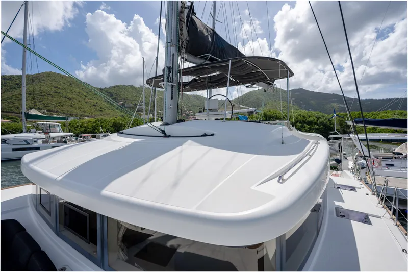 Blue Octane Yacht Photos Pics 2018 Lagoon 52 F catamaran docked, surrounded by lush green hills and blue sky.