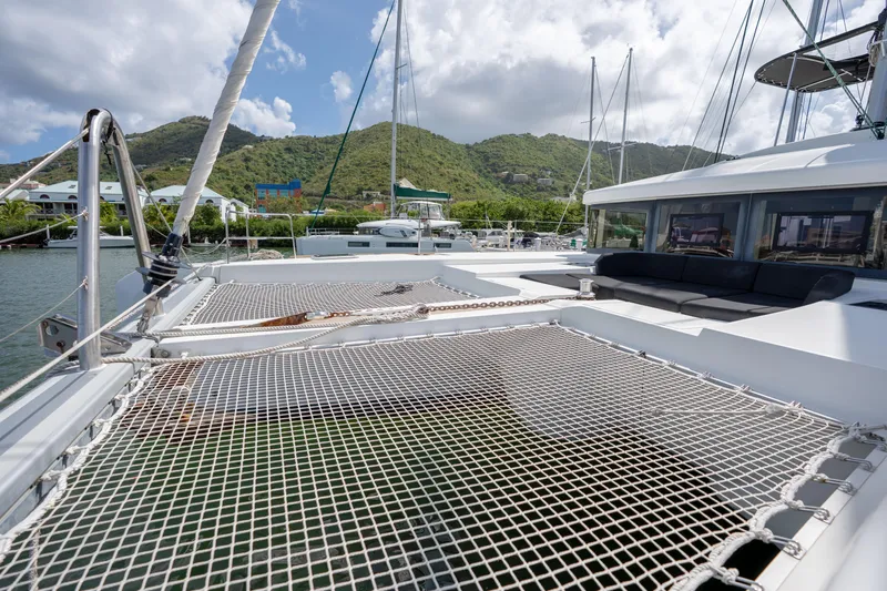 Blue Octane Yacht Photos Pics 2018 Lagoon 52 F catamaran with netting, docked near lush green hills.