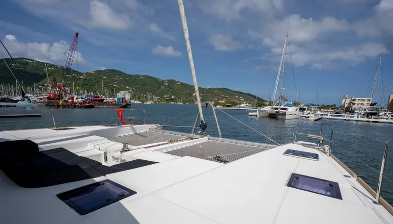 Blue Octane Yacht Photos Pics Lagoon 52 F catamaran docked in a scenic marina with hills and boats.