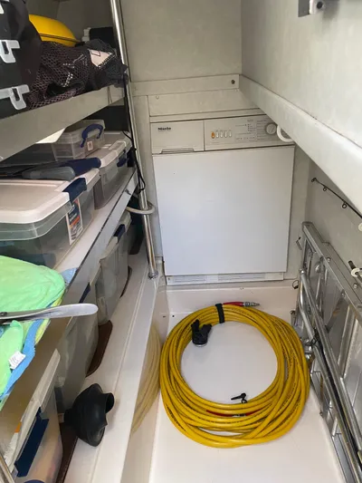 Mercia Yacht Photos Pics Storage area in a 2002 Azimut 55 Flybridge yacht with organized shelves and coiled yellow hose.