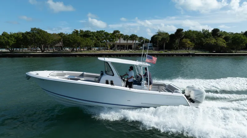  Yacht Photos Pics 2018 Belzona 325 Center Console boat cruising on water, American flag flying.