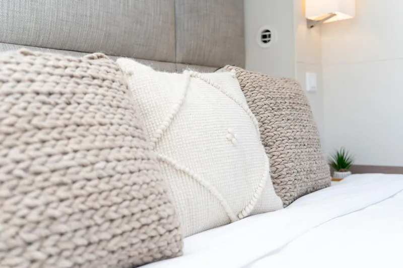 Jewel Yacht Photos Pics Cozy pillows on a bed inside a 2023 Fountaine Pajot Alegria yacht cabin.