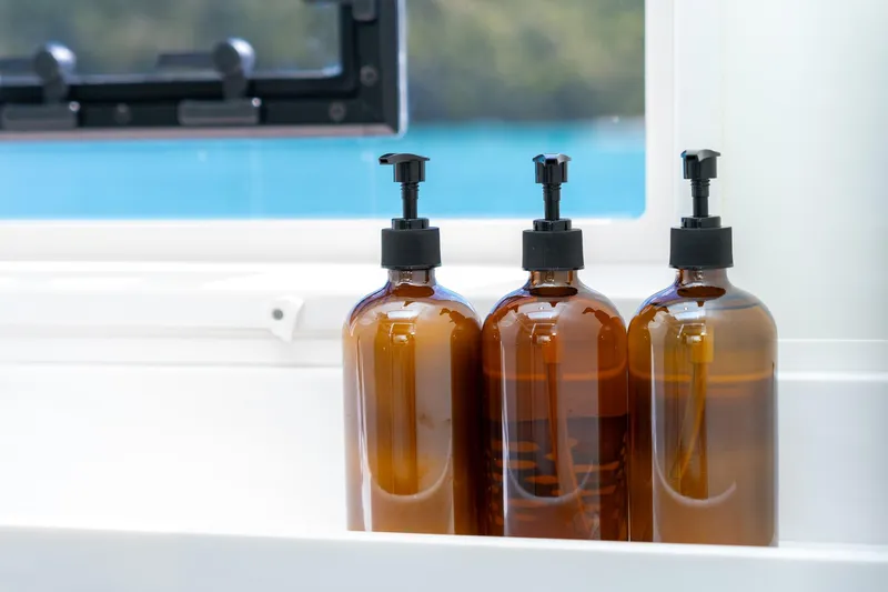 Jewel Yacht Photos Pics Three amber pump bottles on Fountaine Pajot Alegria 2023 yacht, near window with ocean view.