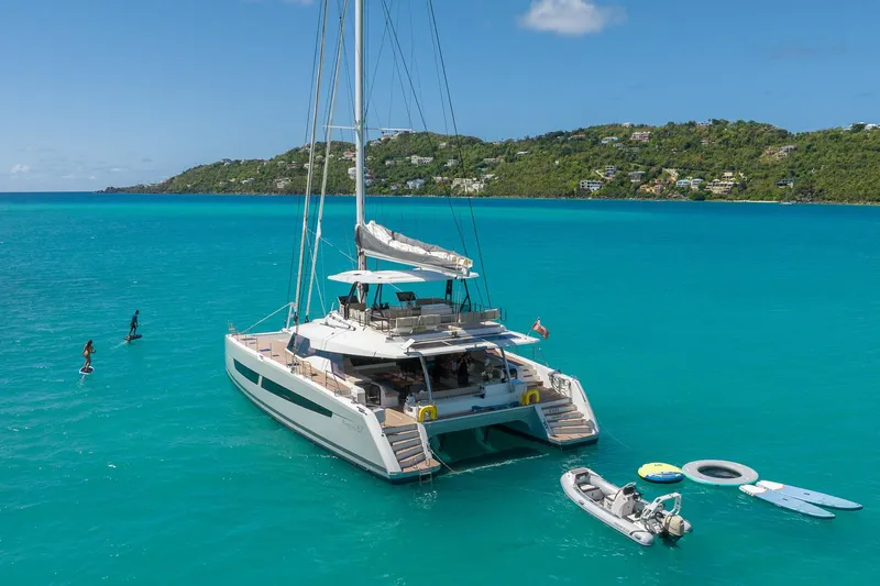 Jewel Yacht Photos Pics 2023 Fountaine Pajot Alegria catamaran anchored in turquoise waters with paddleboarders nearby.