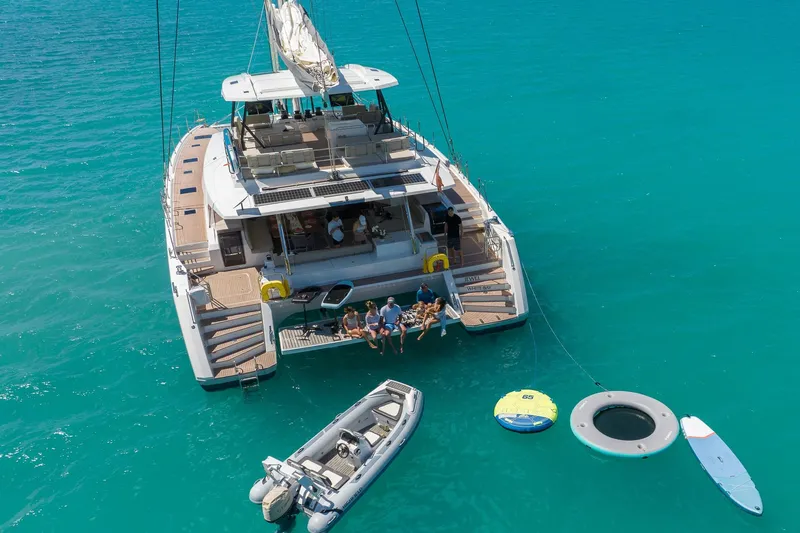 Jewel Yacht Photos Pics 2023 Fountaine Pajot Alegria catamaran with people relaxing, surrounded by turquoise water and water toys.