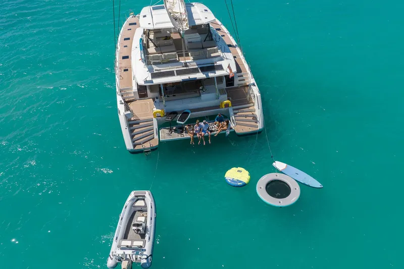 Jewel Yacht Photos Pics 2023 Fountaine Pajot Alegria catamaran with people enjoying water activities in turquoise sea.