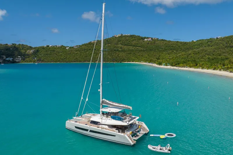 Jewel Yacht Photos Pics 2023 Fountaine Pajot Alegria catamaran anchored in turquoise bay with lush green hills.