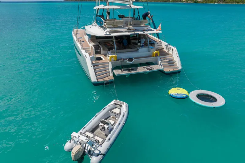 Jewel Yacht Photos Pics 2023 Fountaine Pajot Alegria catamaran anchored in turquoise waters with inflatable toys and dinghy.