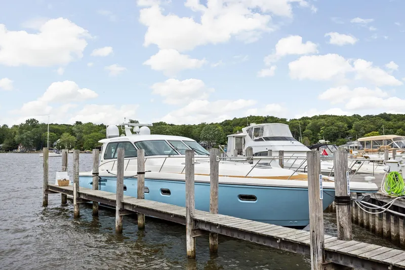 Playpen Yacht Photos Pics 2003 Tiara Yachts 5200 Sovran docked at a marina under a partly cloudy sky.