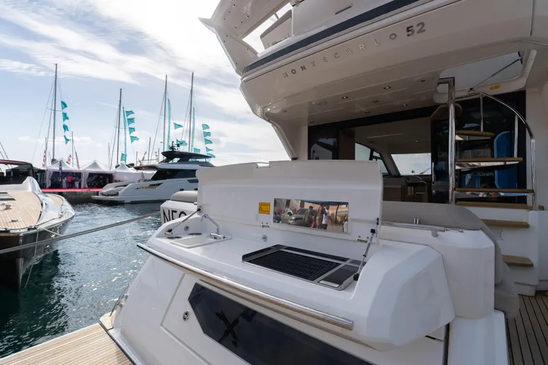  Yacht Photos Pics 2022 Monte Carlo 52 yacht with outdoor kitchen at marina, surrounded by other boats.
