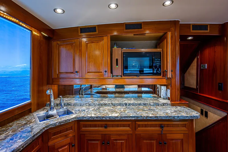 Will Rise Yacht Photos Pics Luxurious kitchen interior of 2005 Custom Carolina 58 yacht with granite countertops and wooden cabinetry.
