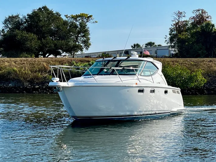 " Toes In The Sand " Yacht Photos Pics 2011 Tiara Yachts Sovran cruising on calm water near green shoreline.