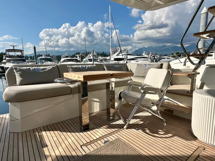 Pearl Voyage Yacht Photos Pics Luxurious 2023 Prestige 520 yacht deck with seating, table, and marina view under a blue sky.