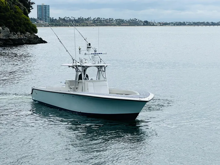 Part Time Hooker Yacht Photos Pics 2009 SeaVee IPS boat cruising on calm waters near a rocky shoreline.