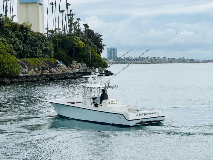 Part Time Hooker Yacht Photos Pics 2009 SeaVee IPS boat cruising near a lush, rocky shoreline under a cloudy sky.