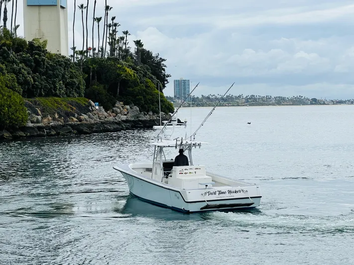 Part Time Hooker Yacht Photos Pics 2009 SeaVee IPS boat cruising near a rocky shoreline with lush greenery.