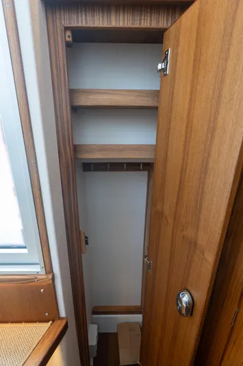 Stock 2 Yacht Photos Pics Wooden storage cabinet inside 2025 Targa 32 GT boat, featuring shelves and hooks.