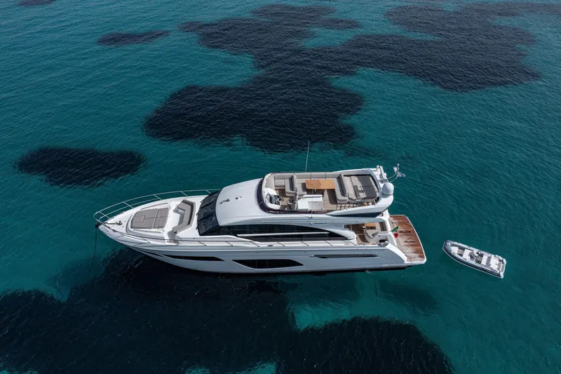  Yacht Photos Pics Luxurious 2020 Princess F70 yacht on clear blue water, with a small boat nearby.