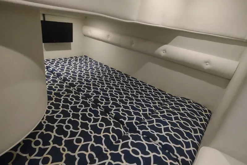  Yacht Photos Pics 2017 Rinker EX 320 cabin interior with patterned bedding and wall-mounted TV.
