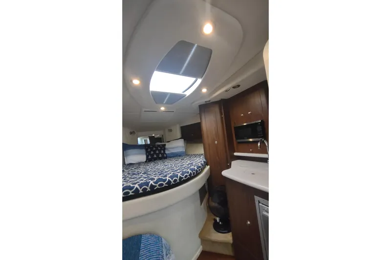  Yacht Photos Pics 2017 Rinker EX 320 cabin interior with bed, skylight, and kitchenette.