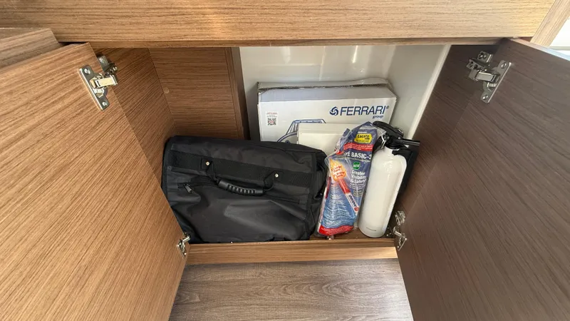 Scrimshaw III Yacht Photos Pics Storage cabinet on 2024 Jeanneau 895 Sport boat with safety equipment and bag.