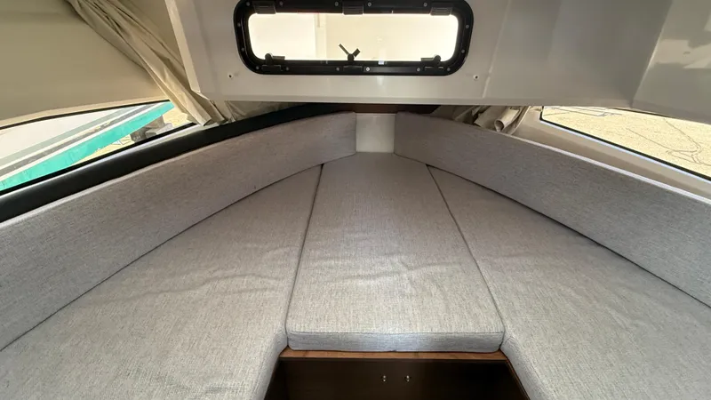 Scrimshaw III Yacht Photos Pics 2024 Jeanneau 895 Sport cabin interior with gray cushions and window.