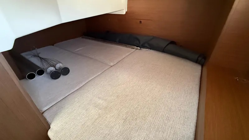 Scrimshaw III Yacht Photos Pics 2024 Jeanneau 895 Sport cabin interior with beige cushions and storage space.