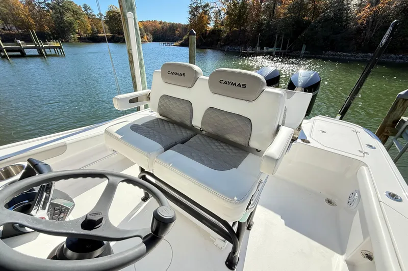  Yacht Photos Pics 2023 Caymas 281 HB boat interior with dual seats and steering wheel, docked by a scenic lake.