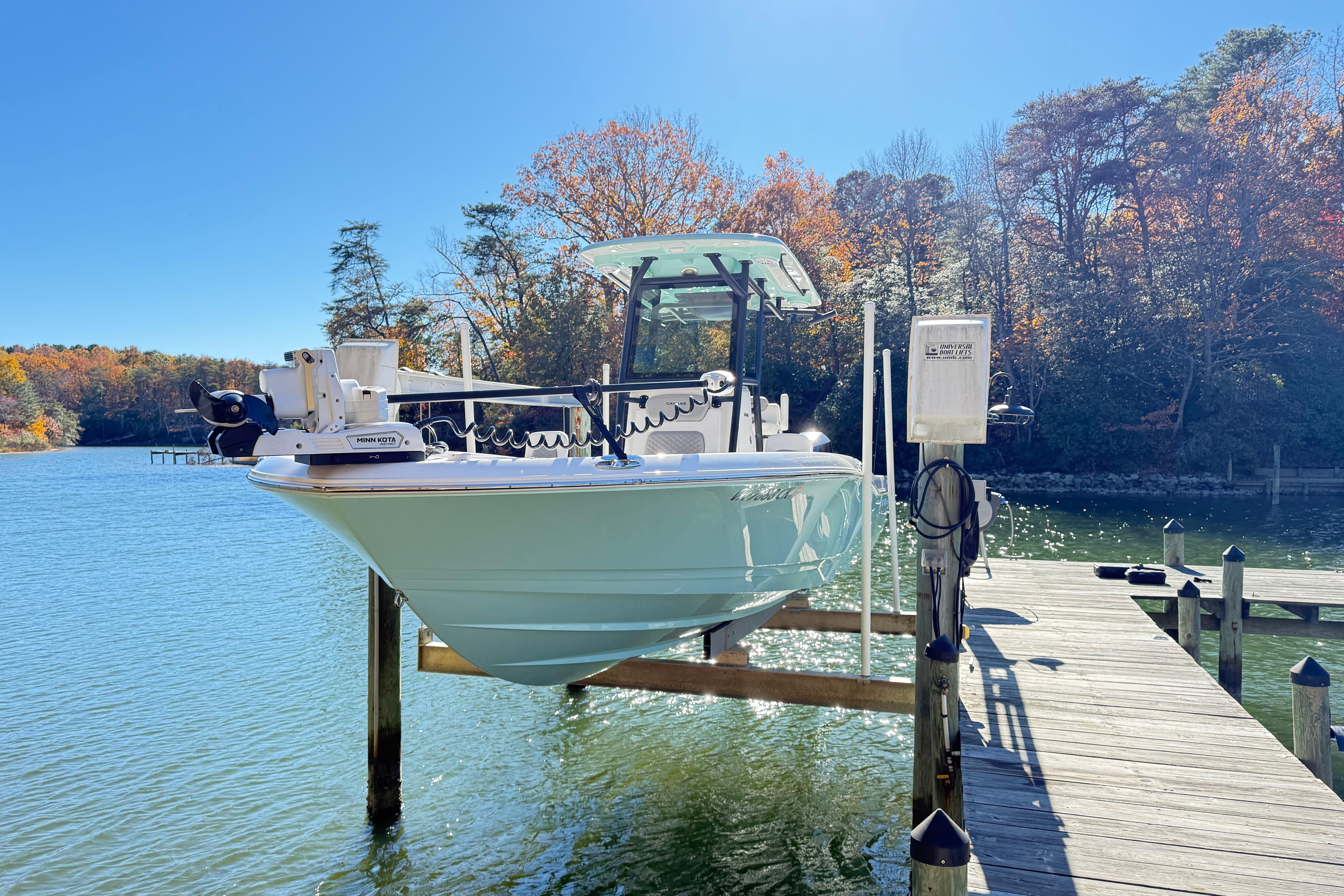 2023 Caymas 281 HB boat docked on a sunny lake with autumn trees.