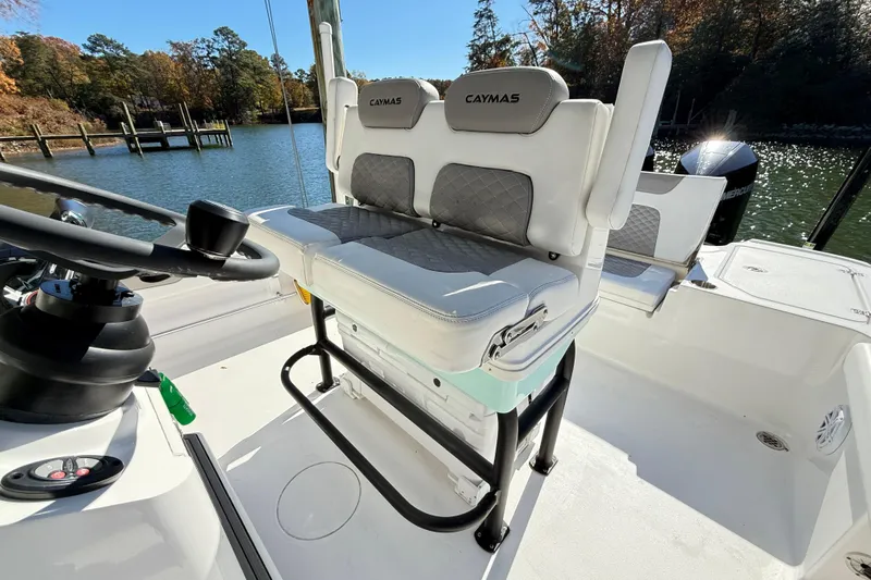  Yacht Photos Pics 2023 Caymas 281 HB boat interior with cushioned seating and steering wheel, docked by a scenic lake.