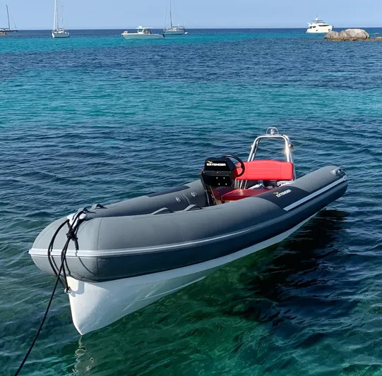 Getaway Yacht Photos Pics Inflatable boat on clear blue water, with sailboats in the background.