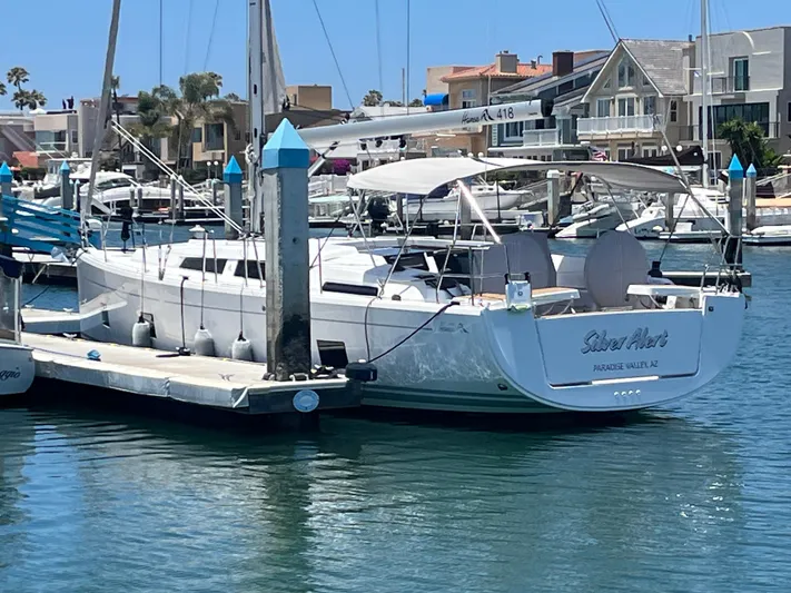 Silver Alert Yacht Photos Pics 2021 Hanse 418 yacht docked in a marina, surrounded by other boats and waterfront homes.