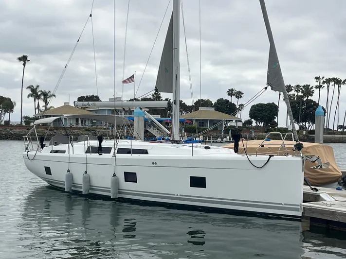 Silver Alert Yacht Photos Pics 2021 Hanse 418 yacht docked in a marina with palm trees and cloudy sky.