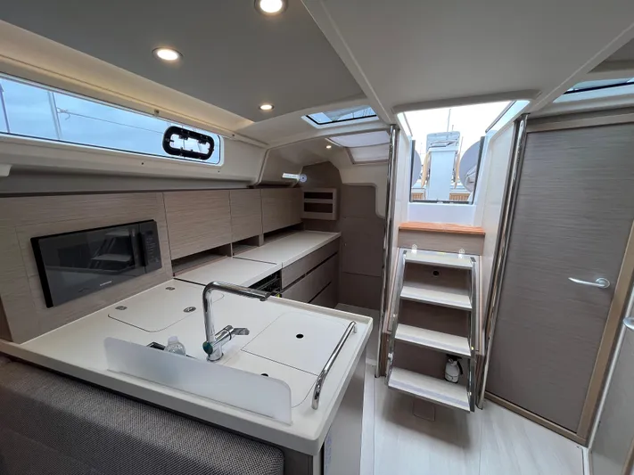 Silver Alert Yacht Photos Pics Modern interior of 2021 Hanse 418 yacht, featuring sleek kitchen and wooden stairs.