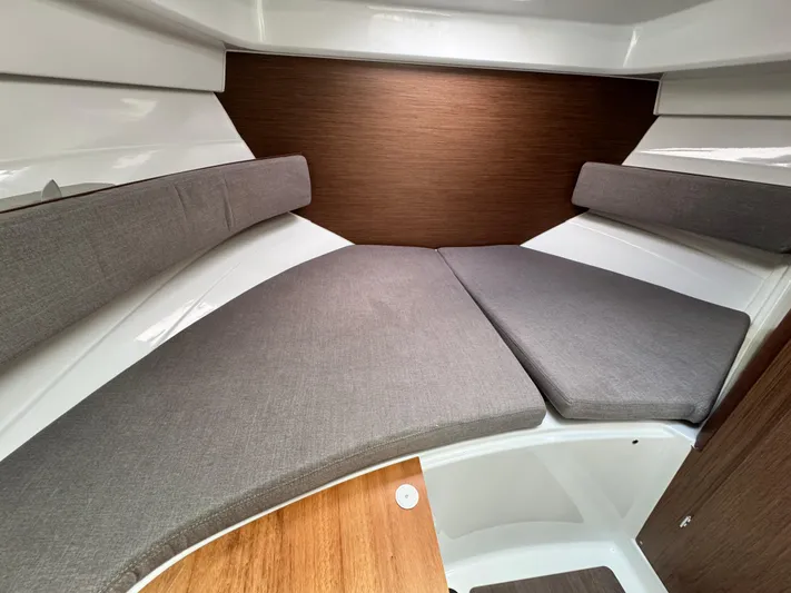  Yacht Photos Pics 2025 Beneteau Antares 8 cabin interior with cushioned seating and wood accents.