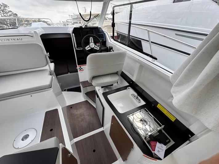  Yacht Photos Pics 2025 Beneteau Antares 8 interior with helm, seating, and kitchenette.