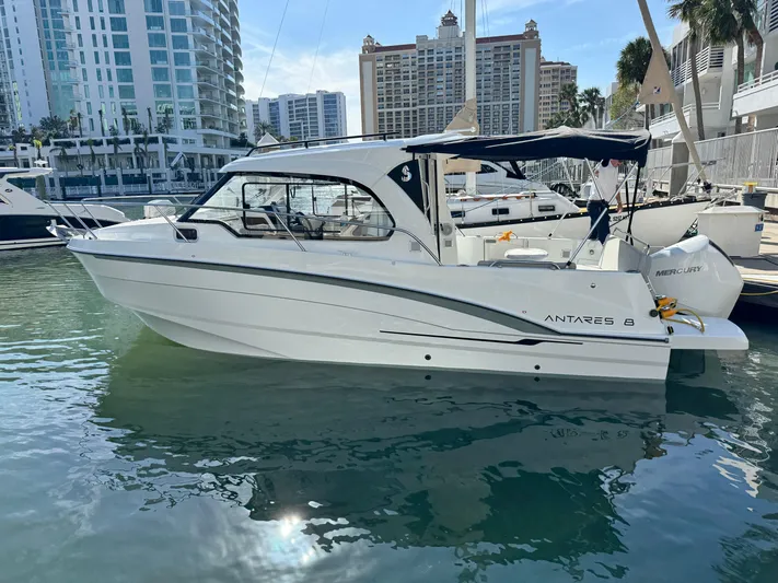  Yacht Photos Pics 2025 Beneteau Antares 8 boat docked in marina, modern cityscape background.