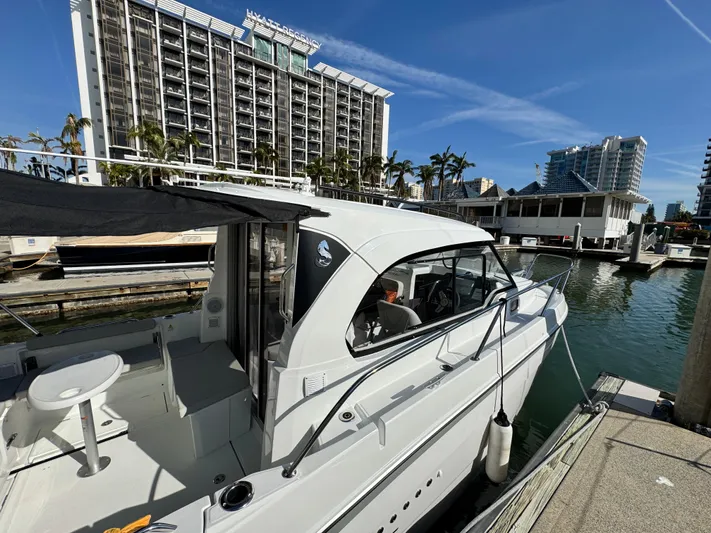  Yacht Photos Pics 2025 Beneteau Antares 8 docked at marina with modern buildings in background.
