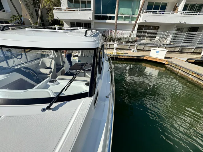  Yacht Photos Pics 2025 Beneteau Antares 8 docked near modern waterfront apartments.