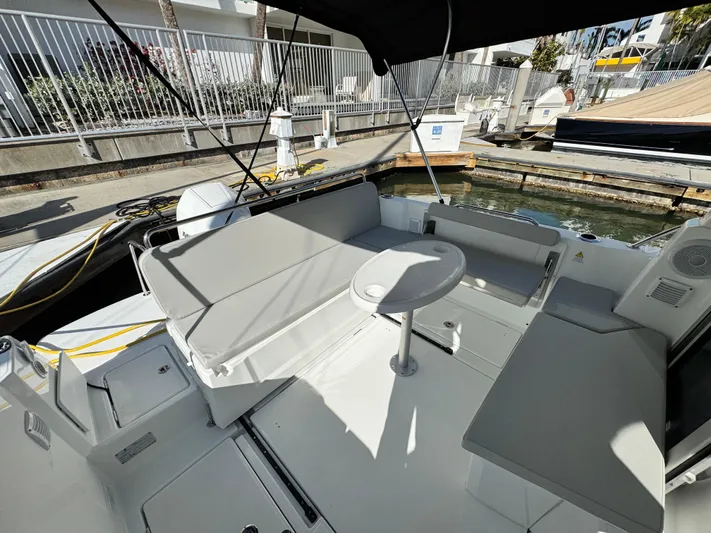  Yacht Photos Pics 2025 Beneteau Antares 8 boat interior with seating and table in marina setting.