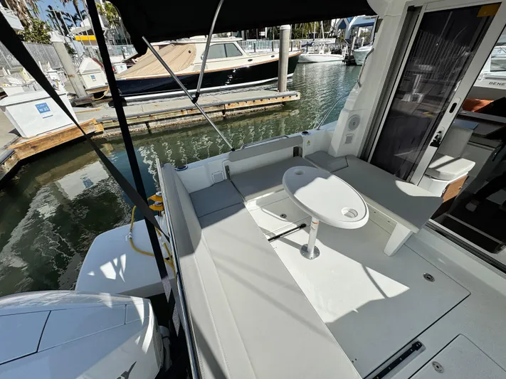  Yacht Photos Pics 2025 Beneteau Antares 8 boat deck with seating and table, docked at marina.