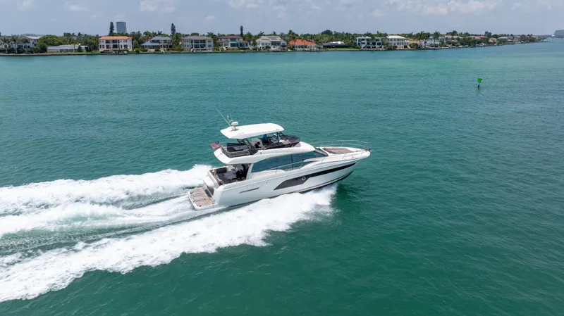 Motivated Seller Yacht Photos Pics 2019 Prestige 520 yacht cruising on turquoise waters near a coastal neighborhood.