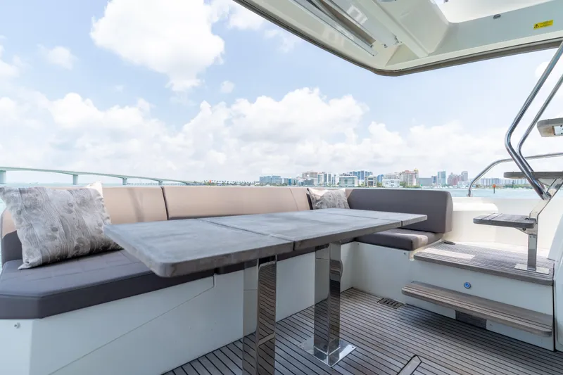 Motivated Seller Yacht Photos Pics Luxurious 2019 Prestige 520 yacht deck with seating, table, and scenic waterfront view.
