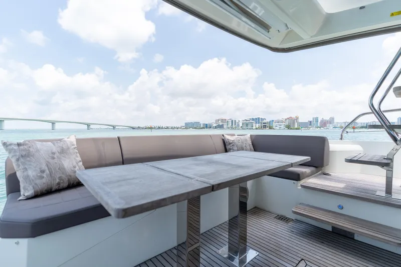 Motivated Seller Yacht Photos Pics Luxurious 2019 Prestige 520 yacht deck with seating, table, and scenic waterfront view.