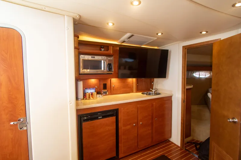 No Name Yacht Photos Pics 2008 Rinker 400 Express Cruiser interior kitchen with microwave, TV, and wooden cabinets.