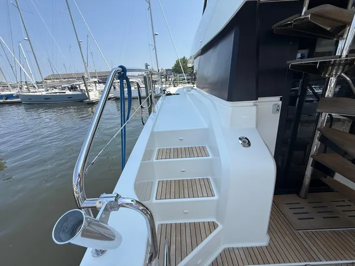 A New Hope Yacht Photos Pics Side view of 2018 Fountaine Pajot MY 44 yacht with wooden steps and marina background.